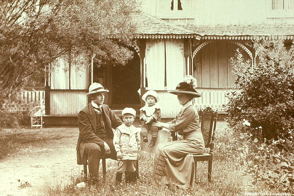 Man, kvinna och två barn i trädgård.