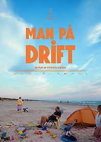 En man sitter i en solstol på en strand omgiven av leksaker i plast